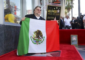 El cineasta mexicano Guillermo del Toro posa con la bandera de México tras una ceremonia en su honor para develar su estrella en el Paseo de la Fama de Hollywood el martes 6 de agosto de 2019 en Los Angeles. Foto: Willy Sanjuan/Invision/AP.