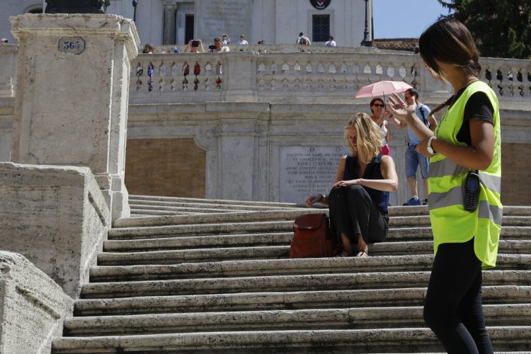 Policía pide a una mujer no sentarse en la escalinata de la Plaza de España en Roma, el miércoles 7 de agosto de 2019. Foto: Gregorio Borgia / AP.