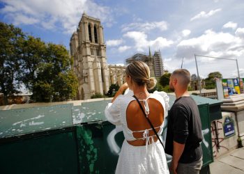 Unos turistas observan la catedral de Notre Dame antes del inicio de una gran descontaminación de plomo en París, Francia. Foto: Francois Mori / AP.