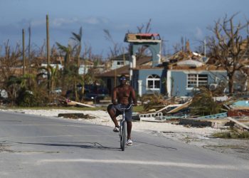 Un hombre pasea en bicicleta entre los escombros provocados por el paso del huracán Dorian, en Marsh Harbor, en la isla de Ábaco, Bahamas, el 6 de septiembre de 2019. (AP Foto/Fernando Llano)
