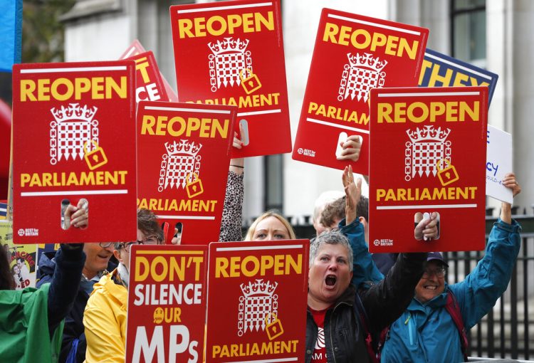 Activistas contrarios al Brexit protestan delante del Supremo en Londres el martes 24 de septiembre de 2019, cuando se decidía sobre la legalidad de la suspensión parlamentaria. Los carteles dicen "No silencien a nuestros parlamentarios" y "Reabran el Parlamento".  (AP Foto/Frank Augstein)