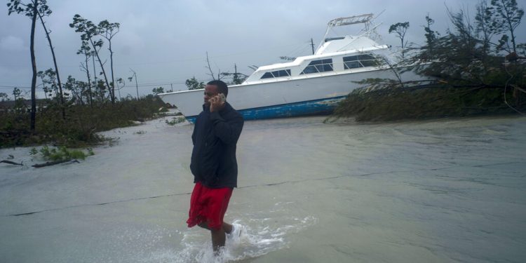 Un hombre habla por teléfono junto a una embarcación varada por el huracán Dorian cerca de la autopista cerrada en Freeport, Gran Bahama, Bahamas, el martes 3 de septiembre de 2019. (AP Foto/Ramón Espinosa)