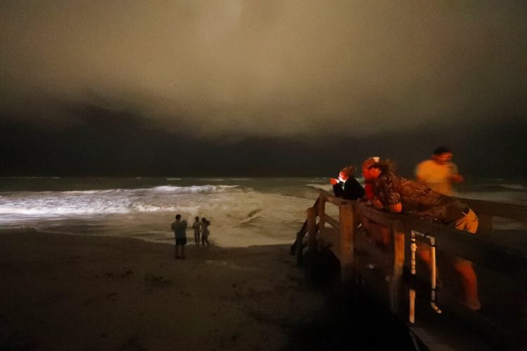 Varias personas caminan por el malecón mientras las bandas exteriores del huracán Dorian llegan a Vero Beach, Florida, la noche del lunes 2 de septiembre de 2019. (Foto AP/Gerald Herbert)