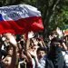 Los manifestantes ondean una bandera chilena pintada con el mensaje "Piñera renuncia" durante una manifestación en Santiago, Chile, el lunes 21 de octubre de 2019. (AP Foto / Miguel Arenas)