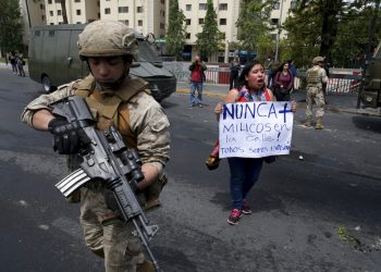 Una mujer protesta junto a un soldado en Santiago de Chile este sábado 19 de octubre. Foto: Esteban Felix/AP.