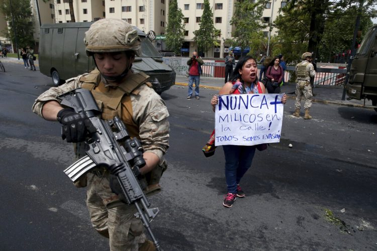 Una mujer protesta junto a un soldado en Santiago de Chile este sábado 19 de octubre. Foto: Esteban Felix/AP.