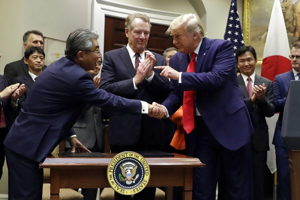 El presidente Donald Trump señala al embajador de Japón en Estados Unidos, Shinsuke Sugiyama, mientras el Representante Comercial de Estados Unidos, Robert Lighthizer, al centro, observa, el final de la ceremonia de una firma de acuerdo comercial con Japón en la Casa Blanca, el lunes 7 de octubre de 2019, en Washington. Foto: Evan Vucci / AP.