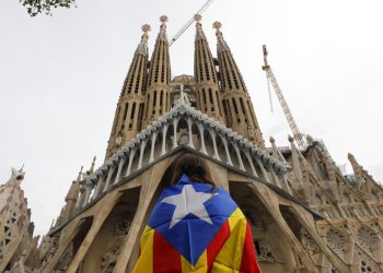 Una manifestante envuelta en la "estelada", la bandera independentista catalana, está frente a la basílica de la Sagrada Familia en Barcelona, España, viernes 18 de octubre de 2019. (AP Foto/Bernat Armangue)