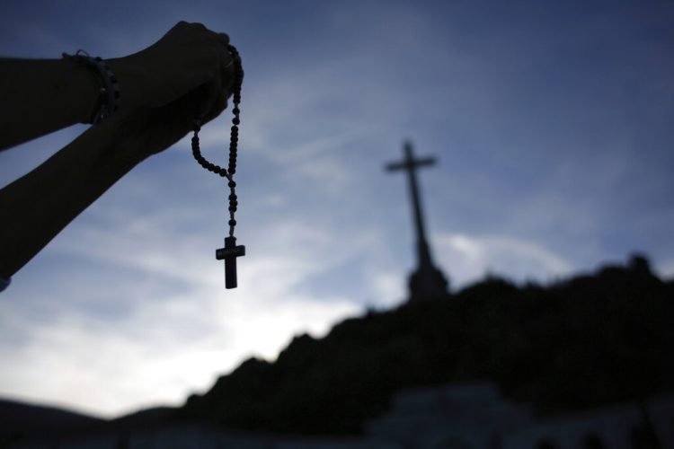 En esta imagen del jueves 3 de octubre de 2019, un fiel sostiene un rosario en el mausoleo del Valle de los Caídos cerca de El Escorial, a las afueras de Madrid, España. Foto: Alfonso Ruiz / AP / Archivo.