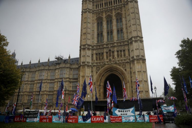 Contrarios al Brexit protestan con banderas europeas y británicas junto a pancartas colocadas por los partidarios de abandonar la Unión Europea, ante el parlamento británico, en Londres, el 24 de octubre de 2019. Foto: Matt Dunham/AP