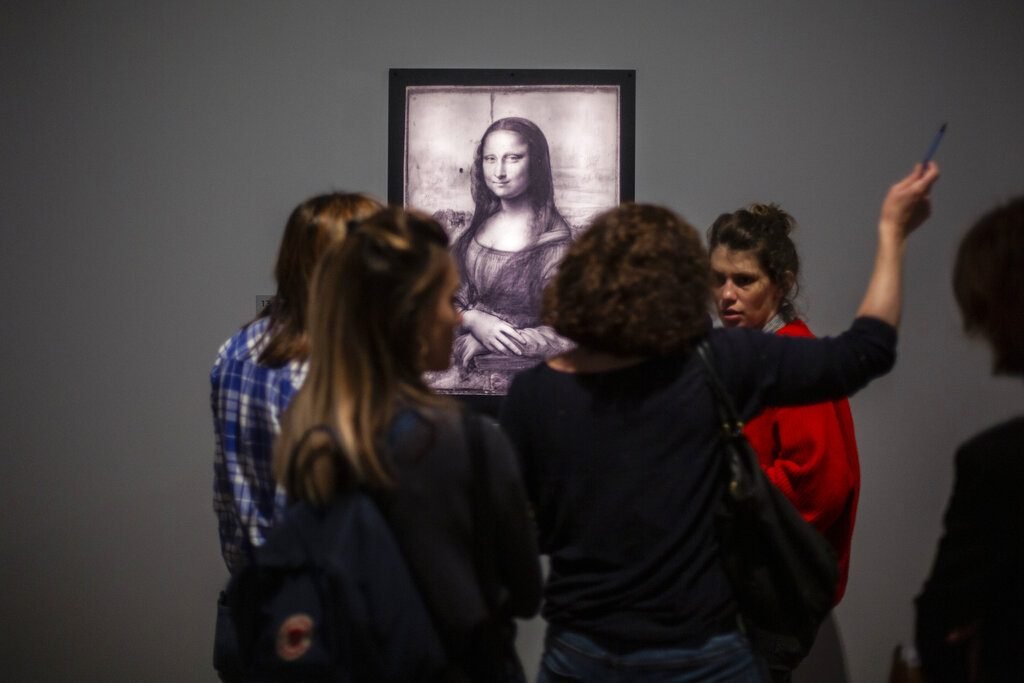 Periodistas se reúnen frente a una imagen de la Mona Lisa de Leonardo Da Vinci durante una visita al Museo del Louvre el domingo 20 de octubre del 2019, en París. Foto: Rafael Yaghobzadeh/AP