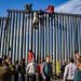 Un grupo de inmigrantes intenta saltar el muro metálico en la frontera con San Diego. Foto: Joebeth Terrique / EFE / Archivo.