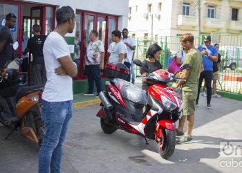 Un pareja junto una moto eléctrica comprada en el servicentro El Tángana, en La Habana, el 28 de octubre de 2019. Foto: Otmaro Rodríguez.