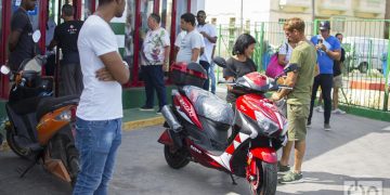 Un pareja junto una moto eléctrica comprada en el servicentro El Tángana, en La Habana, el 28 de octubre de 2019. Foto: Otmaro Rodríguez.