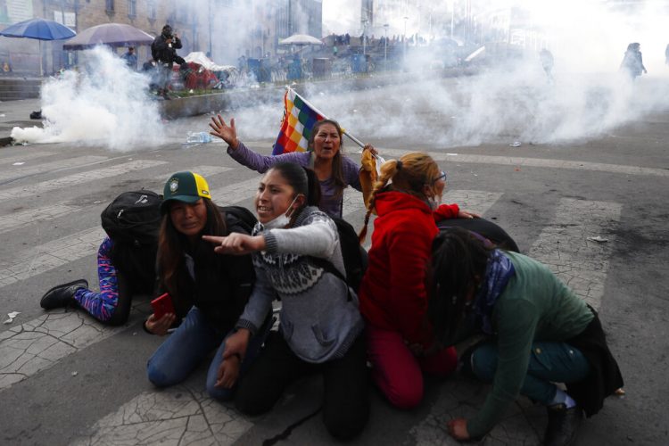 Manifestantes a favor del expresidente boliviano Evo Morales se protegen de las nubes de gas lacrimógeno lanzado por la policía, en La Paz, Bolivia, el 15 de noviembre de 2019. (AP Foto/Natacha Pisarenko)