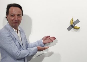 En esta foto del 4 de diciembre del 2019, el dueño de galería Emmanuel Perrotin posa junto a la obra "Comedian" del artista italiano Maurizio Cattlelan durante su exhibición en la feria Art Basel Miami, en Miami Beach, Florida. La obra se vendió por 120.000 dólares. (Siobhan Morrissey vía AP)