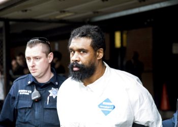 Agentes escoltan a Grafton Thomas desde el ayuntamiento a un vehículo de la policía, el domingo 29 de diciembre de 2019, en Ramapo, Nueva York. Thomas está acusado de apuñalar a varias personas en casa de un rabino al norte de la ciudad de Nueva York. (AP Foto/Julius Constantine Motal)