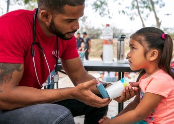 El médico cubano Dairon Elisondo trata a una niña de 4 años, enferma de asma, en un campamento de migrantes en Matamoros, México. Foto: Ilana Panich-Linsman / The New York Times.