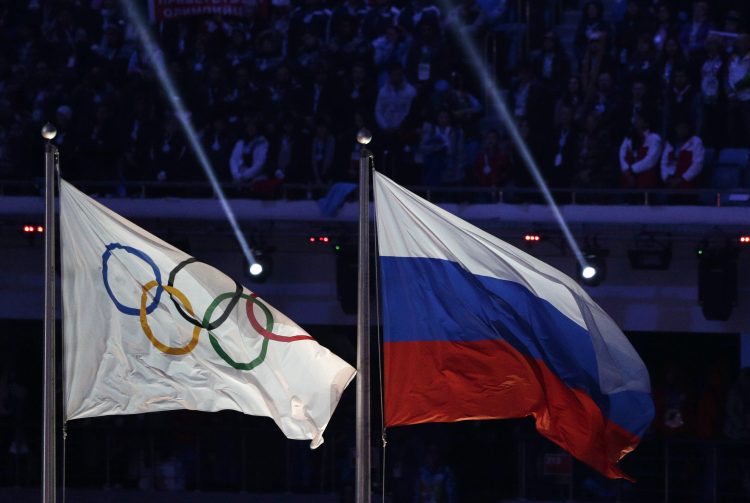 La bandera rusa ondea junto a la bandera olímpica durante la ceremonia de clausura de los Juegos Olímpicos de Invierno de 2014 en Sochi, Rusia.  Esta acusó al principal testigo de la Agencia Mundial Antidopaje (AMA) de modificar importantes datos de laboratorio. Foto: Matthias Schrader/AP.