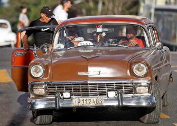 Un grupo de personas suben a un automóvil clásico que funciona como taxi en La Habana (Cuba). Foto: EFE/ Yander Zamora