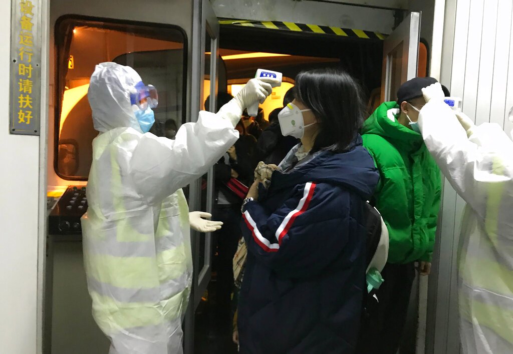 Funcionarios de salud revisan la temperatura corporal de los pasajeros que llegan de la ciudad de Wuhan al aeropuerto de Beijing, el miércoles 22 de enero de 2020. Foto: AP/Emily Wang