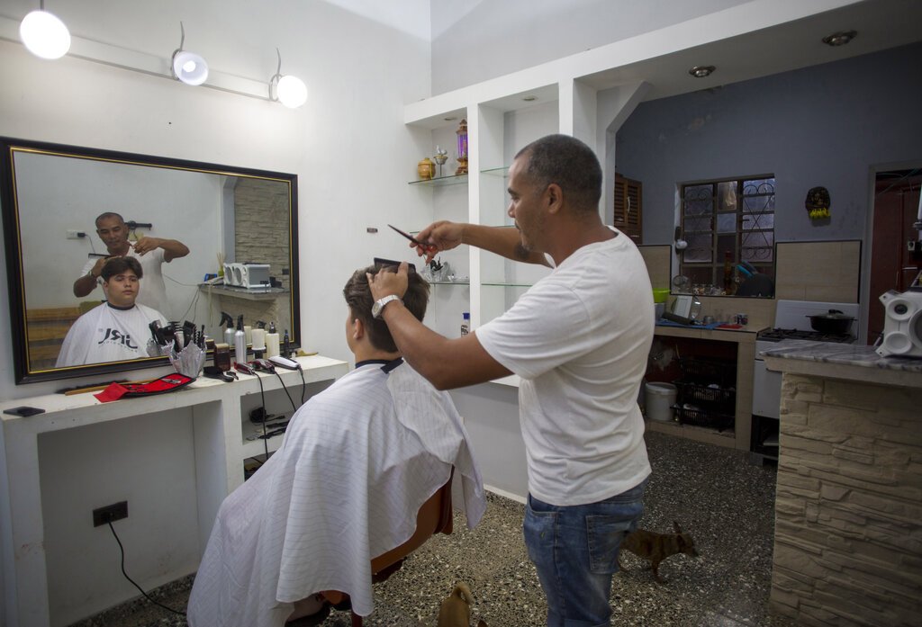 El barbero Yacel Shang, quien fue deportado de México cuando intentaba llegar a Estados Unidos, corta el cabello a un cliente en su barbería instalada en su casa en La Habana, Cuba, el sábado 11 de enero de 2020. Foto: AP/Ismael Francisco