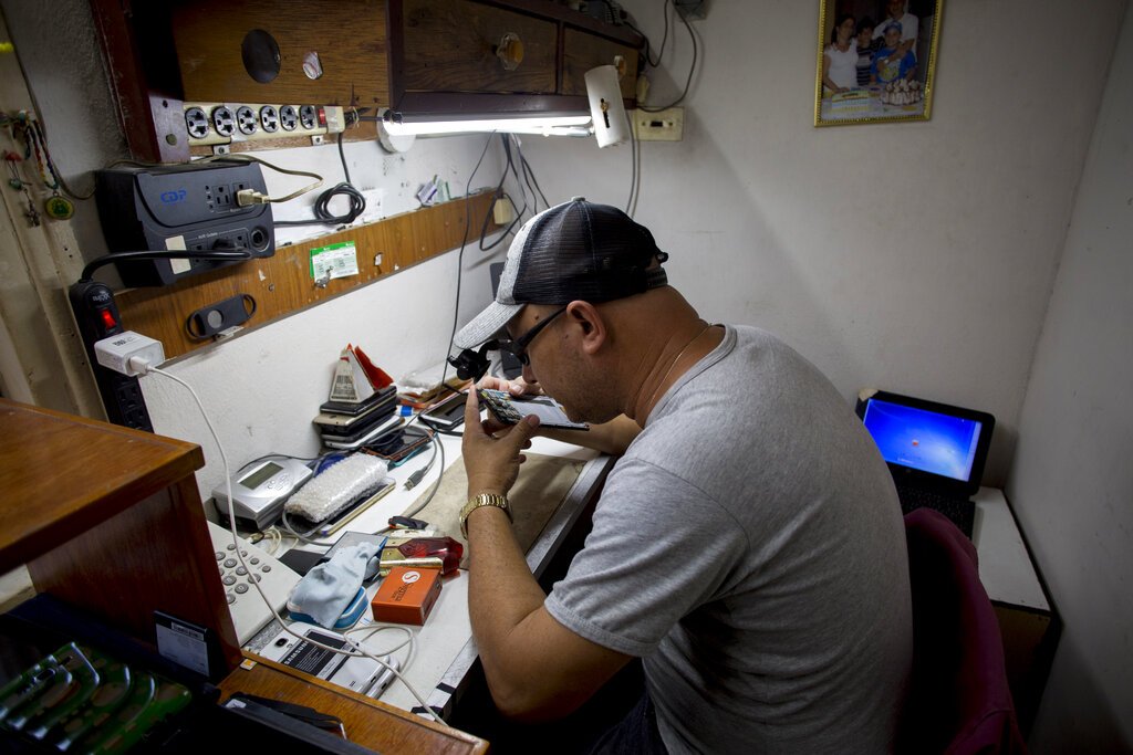 Eduardo Mujica, un técnico de reparación de teléfonos celulares, trabaja en su taller establecido en su casa en La Habana, Cuba, el sábado 11 de enero de 2020. Foto: AP/Ismael Francisco