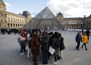 Turistas esperan y empleados en huelga se manifiestan en la entrada al Museo del Louvre, París, viernes 17 de enero de 2020. El museo estaba cerrado en medio de huelgas contra el plan del gobierno de reformar el sistema jubilatorio. (AP Foto/Francois Mori)