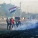 Manifestantes ondeando la bandera nacional mientras las fuerzas de seguridad lanzan gas lacrimógeo a una protesta en el centro de Bagdad, Irak, el lunes 20 de enero de 2020. Foto: AP/Hadi Mizban