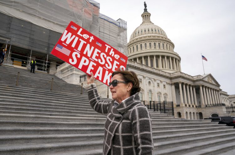 Laura Albinson muestra un cartel mientras abandona el Capitolio, en Washington, el viernes 10 de enero de 2020. (AP Foto/J. Scott Applewhite)