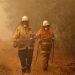 Dos bomberos arrastran una manguera de agua tras apagar un incendio cerca de Moruya, Australia, el 4 de enero de 2020. Foto: Rick Rycroft / AP.