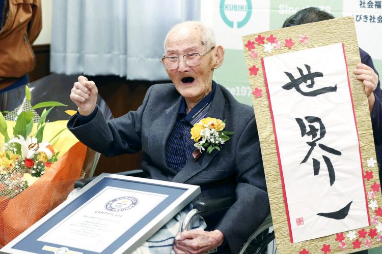 Chitetsu Watanabe, de 112 años, posa junto a un cartel que escribió tras ser condecorado como el hombre más viejo del mundo por el Guinness World Records. (Kyodo News via AP)
