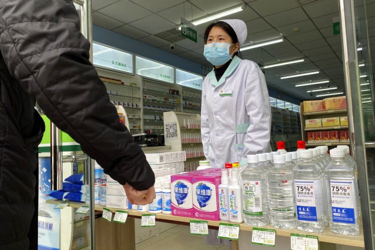 Una farmacéutica atiende a clientes en la entrada de una tienda en Beijing, China, el 20 de febrero de 2020. Foto: Ng Han Guan / AP.