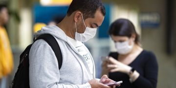Pasajeros usando mascarillas como precaución contra el contagio del nuevo coronavirus usan sus teléfonos en el Aeropuerto Internacional de Sao Paulo, Brasil, el jueves 27 de febrero de 2020. Foto: Andre Penner / AP.