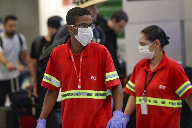 Los empleados del aeropuerto usan máscaras como precaución contra la propagación del nuevo coronavirus COVID-19 mientras trabajan en el Aeropuerto Internacional de Sao Paulo en Brasil, el miércoles 26 de febrero de 2020. Foto: Andre Penner / AP.