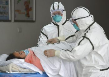 Personal sanitario provisto con trajes protectores traslada a una paciente infectada con coronavirus a un pabellón de aislamiento en el Segundo Hospital del Pueblo en Fuyang, provincia de Anhui, en el centro de China, a inicios de la pandemia. Foto: Chinatopix vía AP.