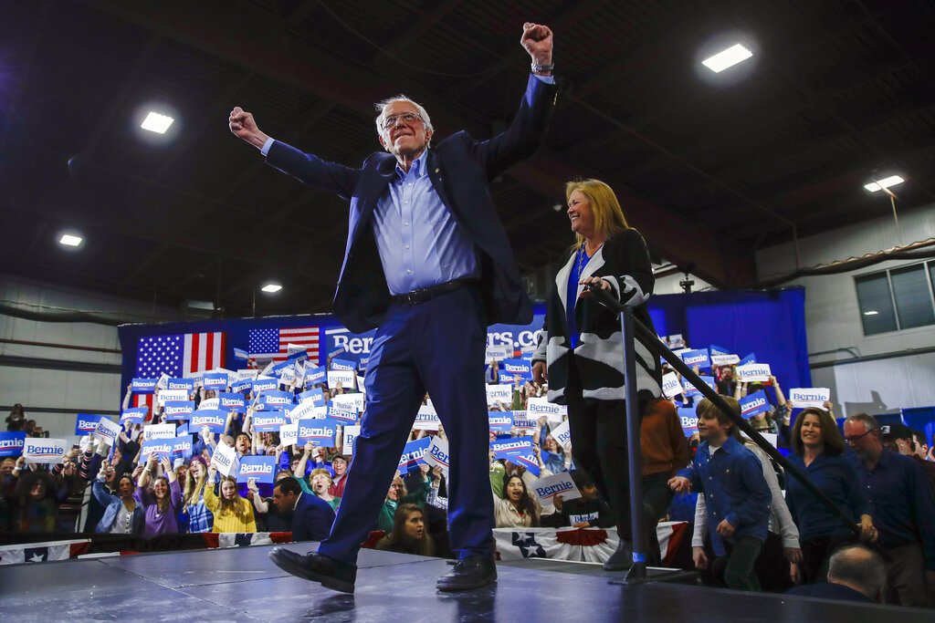 El precandidato presidencial demócrata y senador Bernie Sanders, acompañado por su esposa, Jane O'Meara Sanders, levanta los brazos durante una reunión proselitista en Essex Junction, Vermont, la noche del martes 3 de marzo de 2020. Foto: AP/Matt Rourke.