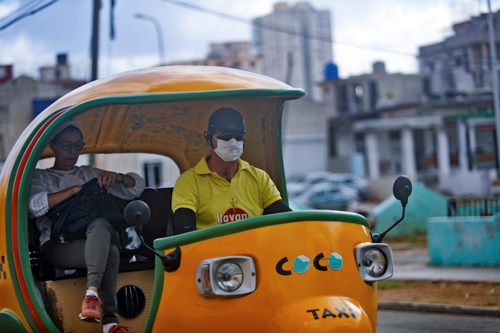 Un chofer de cocotaxi usa un nasobuco como medida de protección contra el coronavirus, en La Habana. Foto: Yander Zamora / EFE.