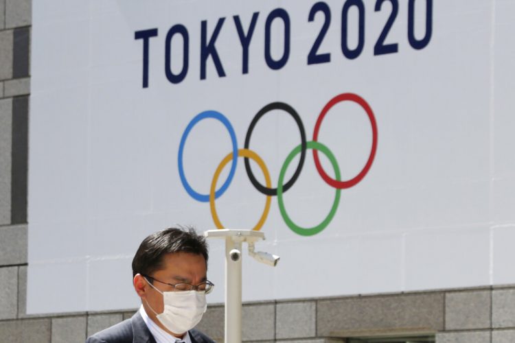 Un hombre con una mascarilla pasa junto a un cartel que anuncia los Juegos Olímpicos de Tokio del 2020, ya pospuestos para el próximo año. Foto: Koji Sasahara / AP / Archivo.