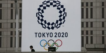 Un hombre pasa junto a un gran cartel promocionando los Juegos Olímpicos de Tokio 2020 en Tokio, marzo de 2020. Foto: AP/Jae C. Hong/Archivo.