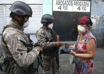 Una mujer explica a los soldados que está buscando alcohol en farmacias, antes de que la dejen continuar su camino, en el tercer día del estado de emergencia en Lima, Perú, el miércoles 18 de marzo de 2020. Foto: Martín Mejia/AP.