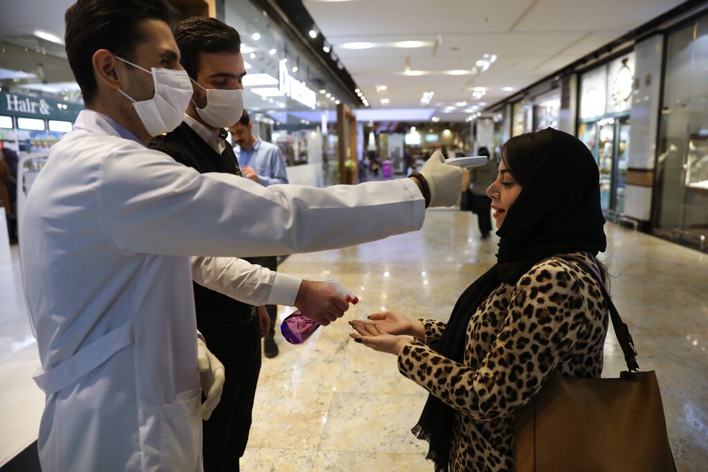 Una mujer se somete a un control de temperatura mientras se desinfecta las manos al entrar al centro comercial Palladium, en Teherán, Irán, el 3 de marzo de 2020. Foto: Vahid Salemi / AP.