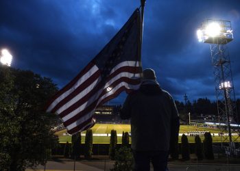 Un hombre sostiene la bandera de Estados Unidos mientras sigue un partido de la Liga de Fútbol de Estados Unidos en Tacoma, Washington. Foto: Joshua Bessex/The News Tribune via AP.