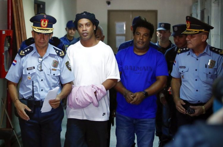 Ronaldinho y su hermano Roberto de Assis Moreira llevados por la policía a declarar ante una jueza de Asunción el 7 de marzo del 2020. Los dos fueron detenidos por ingresar a Paraguay con pasaportes falsos. Foto: Jorge Sáenz/AP.