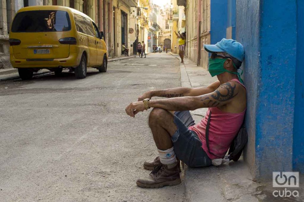 Un hombre sentado en una acera de La Habana, con un nasobuco como medida de protección contra la pandemia de coronavirus. Foto: Otmaro Rodríguez.