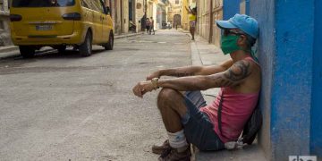 Un hombre sentado en una acera de La Habana, con un nasobuco como medida de protección contra la pandemia de coronavirus. Foto: Otmaro Rodríguez.