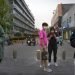 Varias personas cubren sus caras con máscaras como medida contra la propagación del nuevo coronavirus mientras caminan al aire libre por una zona comercial en Beijing, el viernes 24 de abril de 2020.  (AP Foto/Mark Schiefelbein)