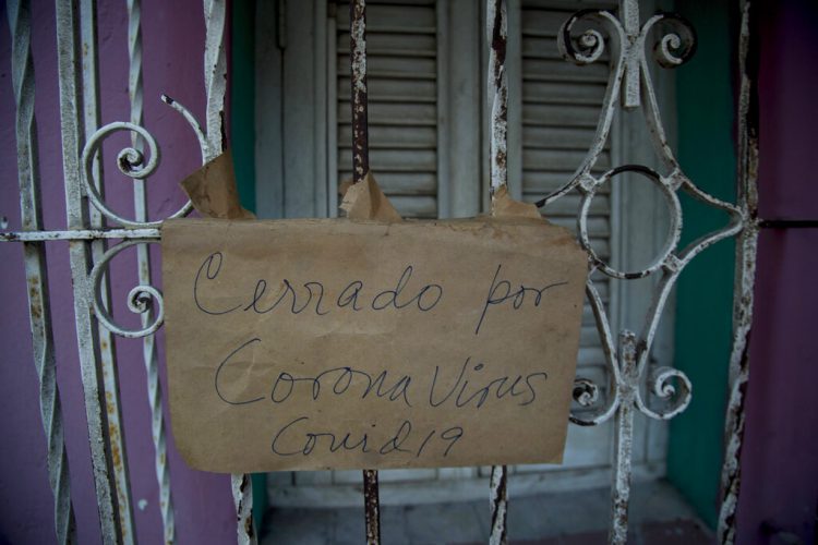Un cartel de "Cerrado por coronavirus COVID-19" cuelga de la puerta de rejas de un negocio en La Habana, Cuba, el viernes 24 de abril de 2020. (AP Foto/Ismael Francisco)