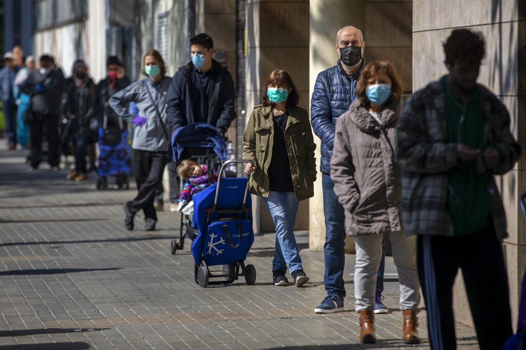Personas con mascarillas se forman para comprar provisiones en una tienda durante el brote del coronavirus en Barcelona, España, el sábado 4 de abril de 2020. Foto: Emilio Morenatti / AP.