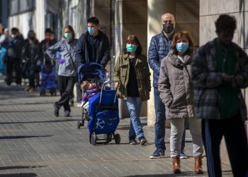 Personas con mascarillas se forman para comprar provisiones en una tienda durante el brote del coronavirus en Barcelona, España, el sábado 4 de abril de 2020. Foto: Emilio Morenatti / AP.